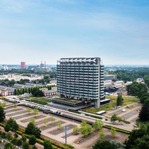 Impressie van het VB Gebouw in Eindhoven met vijf nieuwe woongebouwen in een groene omgeving.
