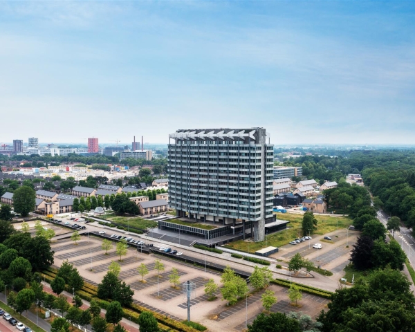 Impressie van het VB Gebouw in Eindhoven met vijf nieuwe woongebouwen in een groene omgeving.